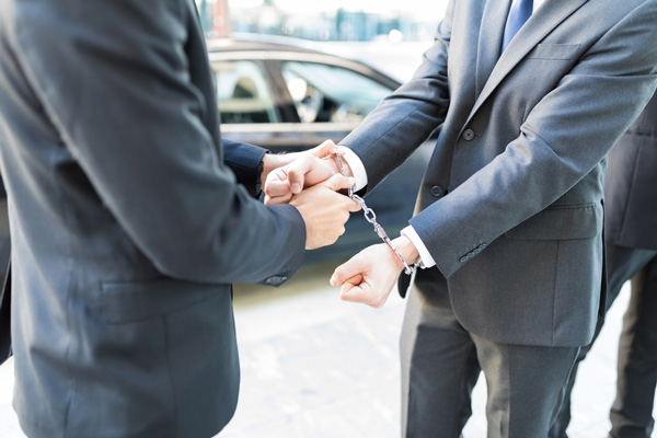 man in suit being handcuffed
